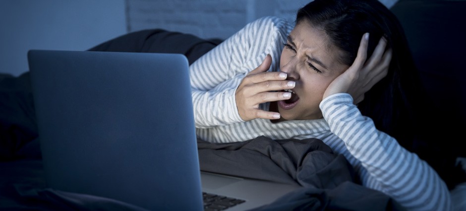 woman yawning in front of laptop