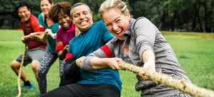a group of people playing tug of war outside