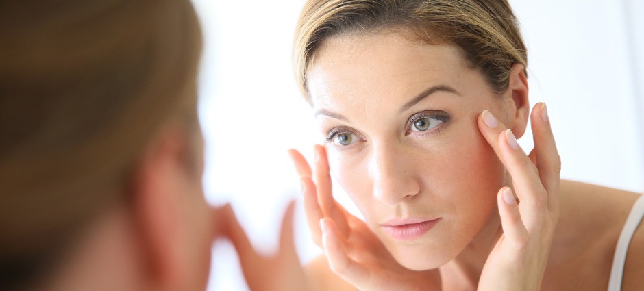 woman applying eye cream in a mirror