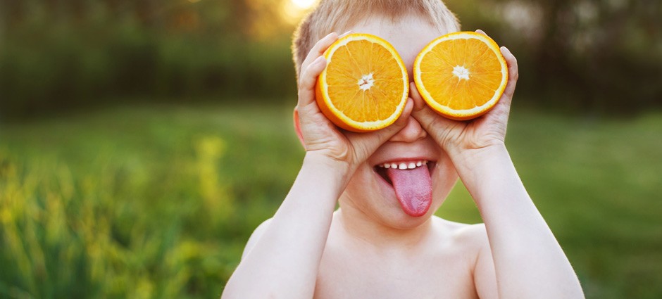 little boy with oranges on his eyes